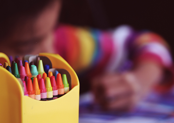 child creating art with crayons